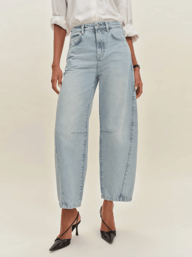 A person wearing light blue wide-leg jeans, a white long-sleeve shirt with rolled-up sleeves, and black pointed-toe heels.