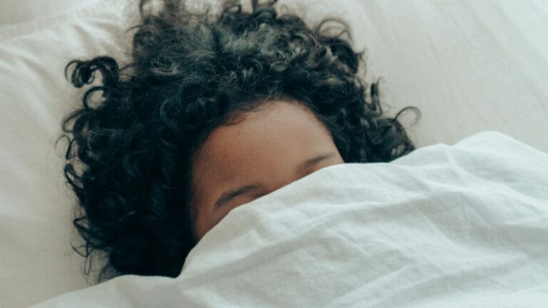 Woman sleeping under white comforter.