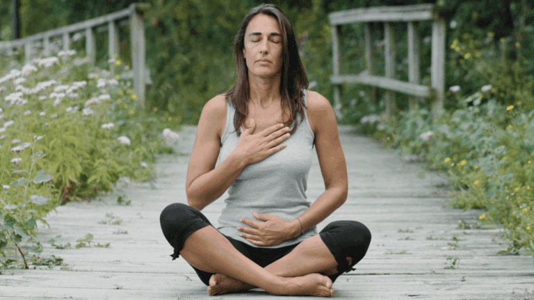 A woman in meditation pose with her hand on her heart, part of a her yin yoga practice