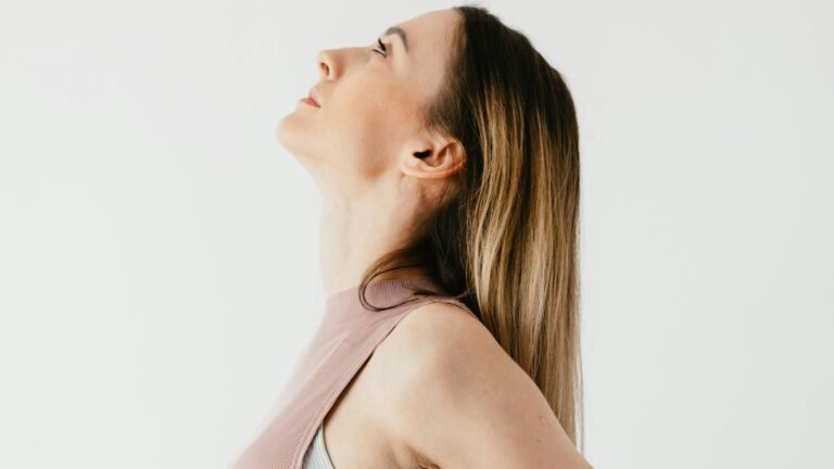 Woman in pink shirt standing with her shoulders drawn back.