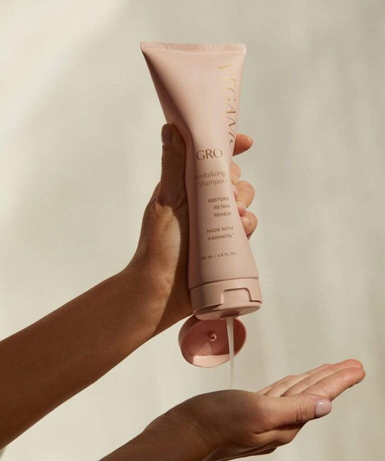 9 champús sin sulfatos y sin disruptores endocrinos A hand dispenses clear shampoo from a pink VEGAMOUR GRO Revitalizing Shampoo bottle into the palm of another hand.