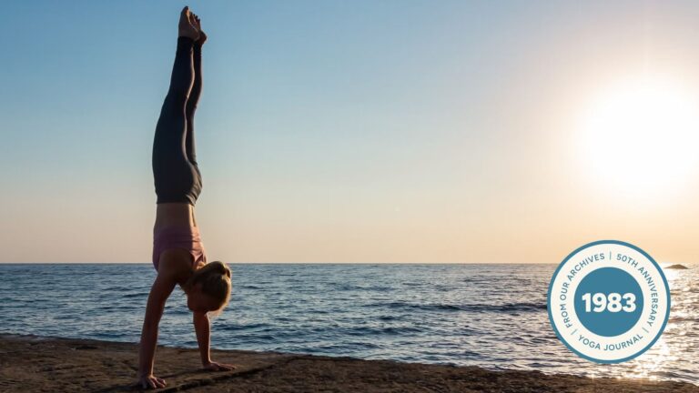 Woman practicing Handstand on the beach at sunset.