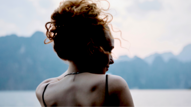 Woman standing outside looking at mountains contemplating her weekly horoscope for December 7-13, 2025.