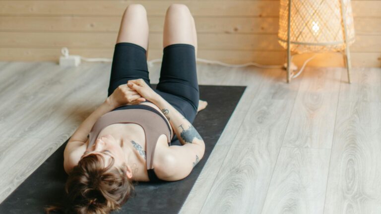 Woman lying on back on yoga mat.