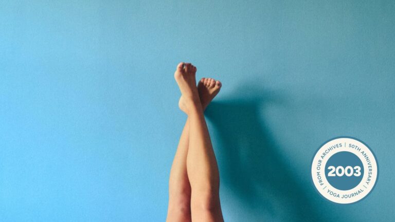 Image of person's legs crossed and resting against a light blue wall.