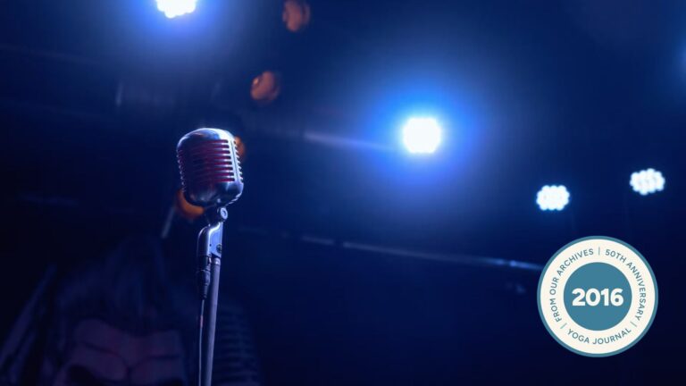 Image of microphone surrounded by darkness with two spotlights blaring down.