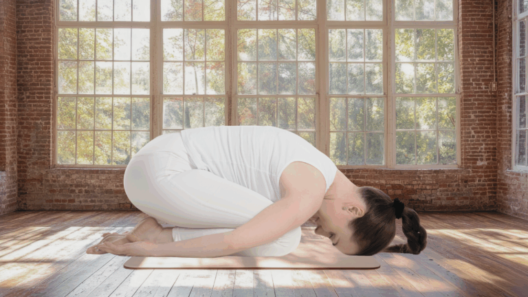 A woman in Child's Pose in a yoga studio