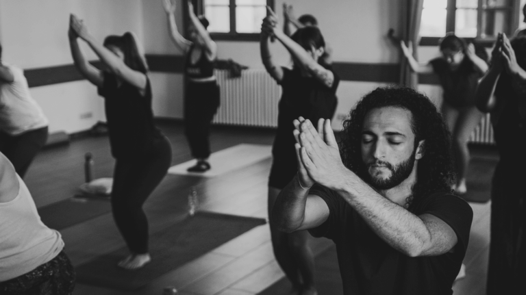 Black and white image of a yoga class with students in Chair Pose