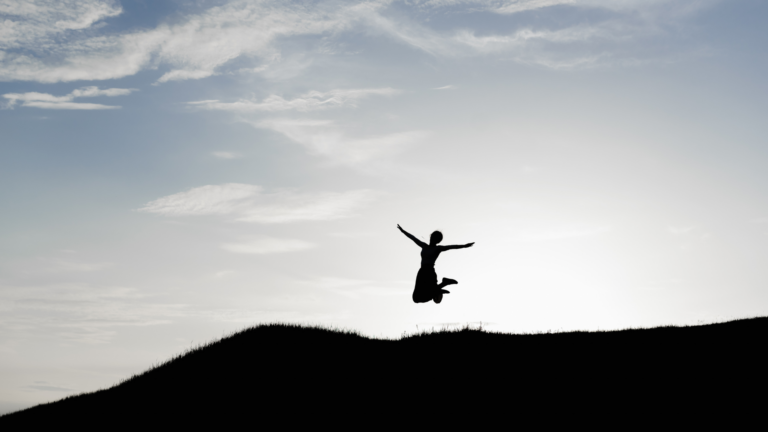 Woman jumping in the air while hiking and contemplating her weekly horoscope