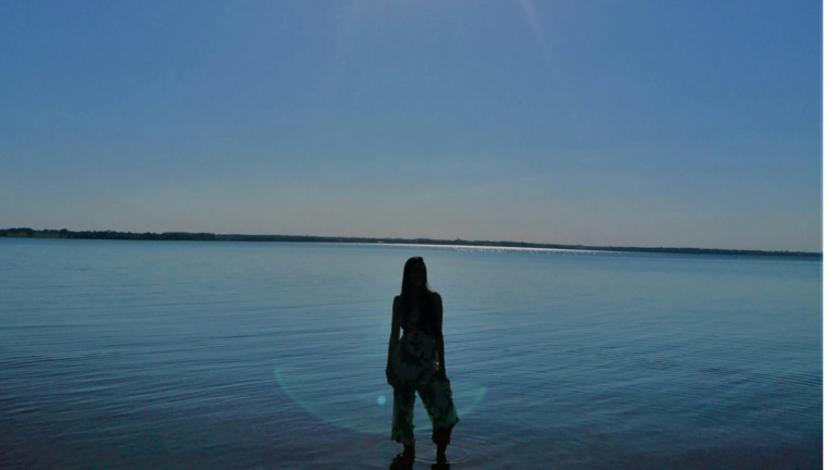 Woman's silhouette standing on the beach after sunset while thinking aout the weekly forecast january 4-10, 2026