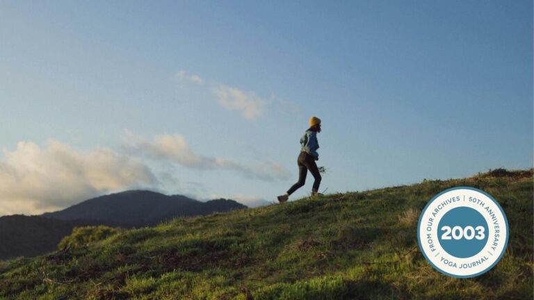 Woman walking up a grassy hill.