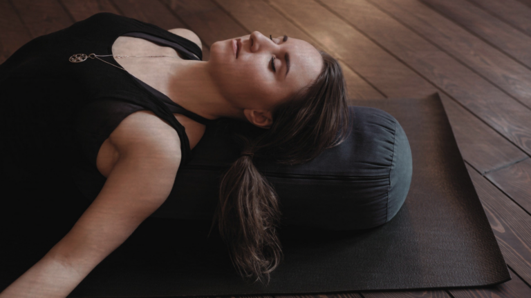 A woman in Supported Fish Pose, part of a yin yoga for stress practice