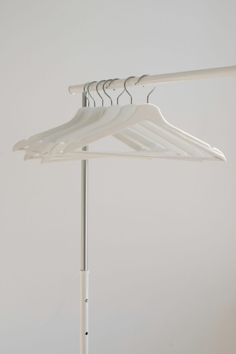 White hangers on a clothing rack against a plain background.