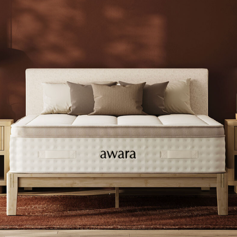 7 Best Mattresses For Hot Sleepers (2026) A bed with a beige headboard, neutral pillows, and an "awara" branded mattress sits between two wooden nightstands against a brown wall.