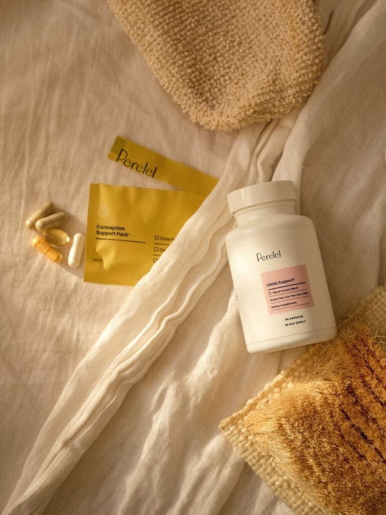 A white bottle labeled "Peretel" sits on a beige fabric next to a yellow packet and several capsules and softgels.