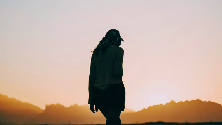 Silhouette of a woman walking toward the sunrise and contemplating her weekly horoscope