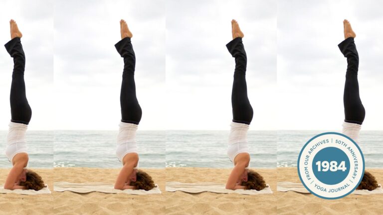 Woman practicing Headstand on the beach.