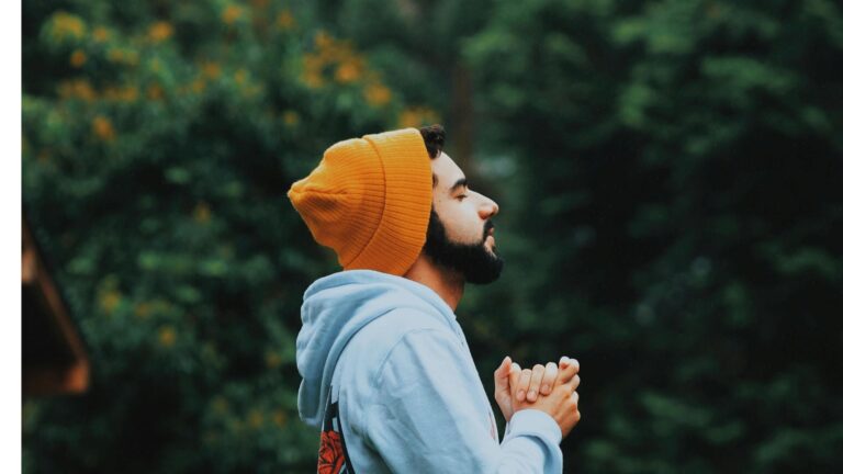 Man with orange beanie on closing his eyes and breathing.