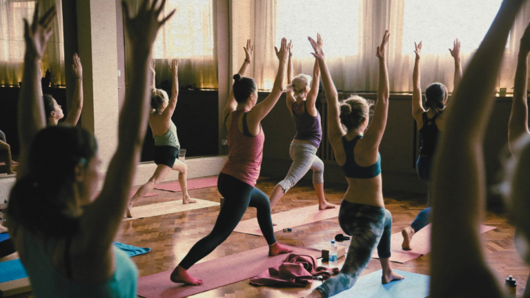 A yoga class practicing high lunge in a studio