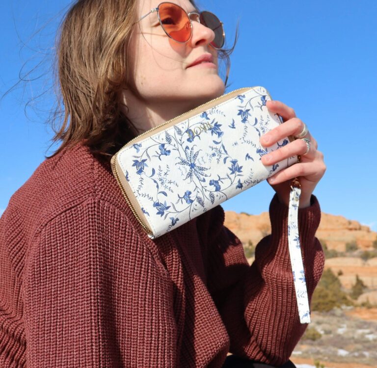 Amber from Sustainable Jungle testing Doshi's Continental Kraft Paper sustainable wallet outdoors — white and blue floral vegan wristlet wallet made from plant-based cellulose, one of the best eco-friendly and sustainable wallets reviewed by Sustainable Jungle