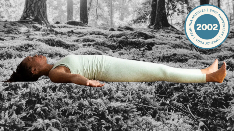 A woman lying in Savasana on a bed of moss