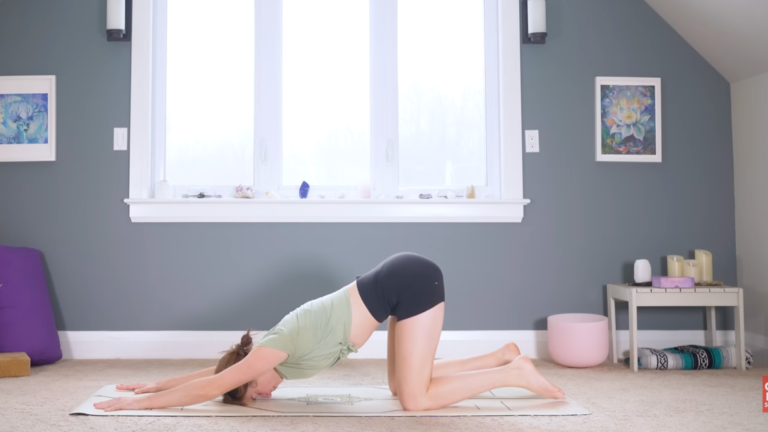 Woman kneeling on a mat with her arms stretched forward and her forehead on the mat in Puppy Pose