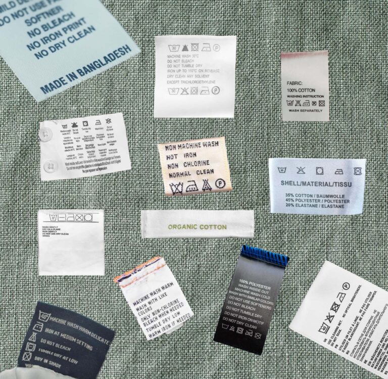 Learn how to read clothing tags, care symbols, and fiber content labels. Image shows a collage of clothing labels on a green fabric backdrop