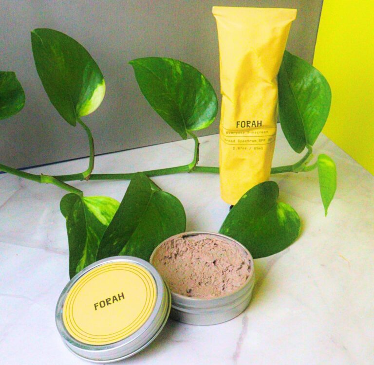 Forah zero waste sunscreen personally tested by Sustainable Jungle, shown in yellow packaging beside a tin of mineral sunscreen and green pothos leaves.
